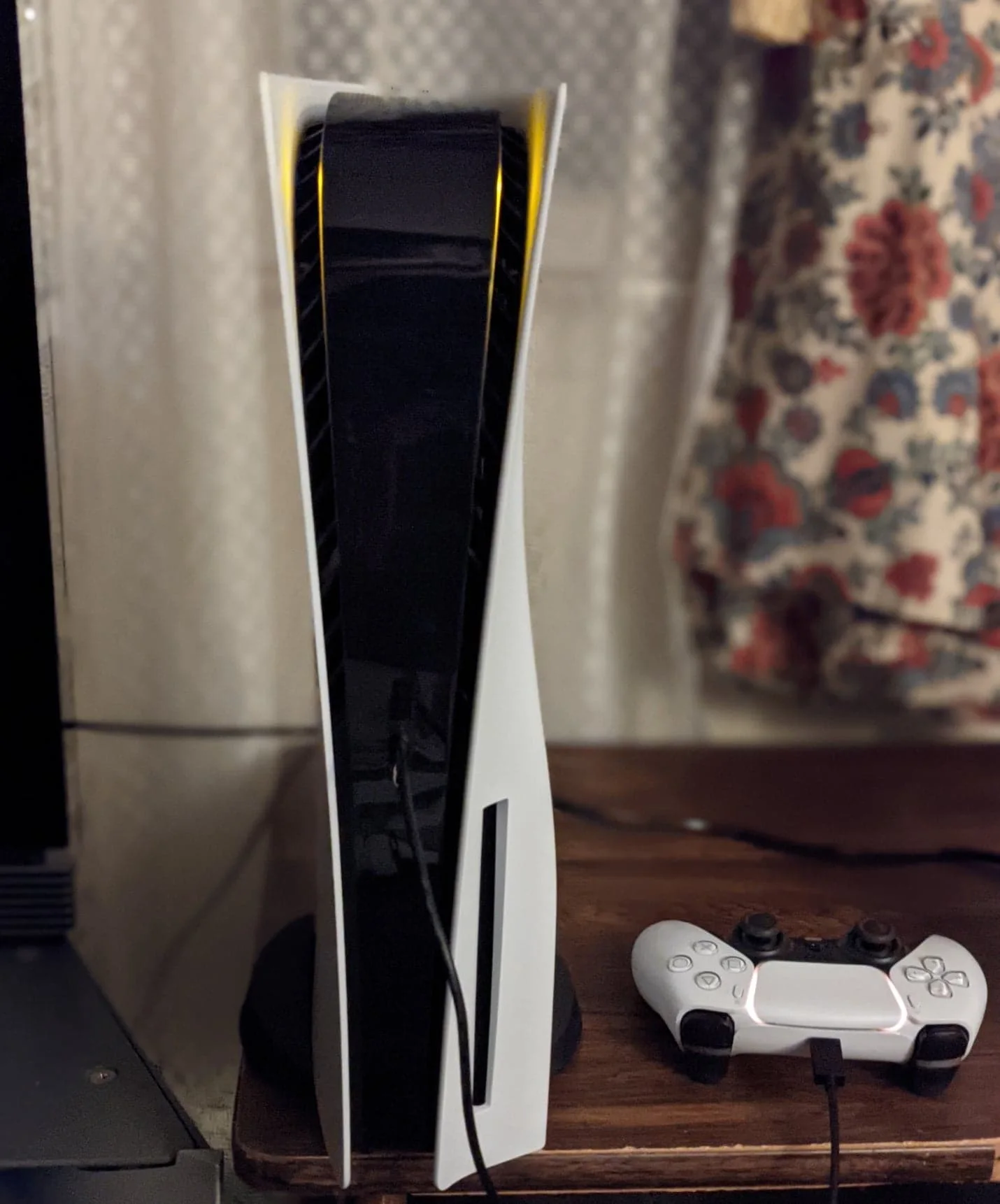 Dikey standda duran PlayStation 5 ve şarj olan DualSense kontrolcü